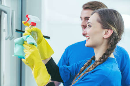 Commercial cleaners cleaning an office window wearing glovesの写真素材