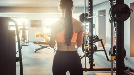 Young woman lifting weights in her private gym seen from behindの写真素材