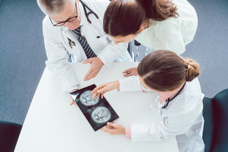 Team of doctors discussing x-ray on a tablet computer working togetherの写真素材