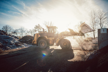 Bulldozer putting biomass on pile for composting in industrial facilityの写真素材