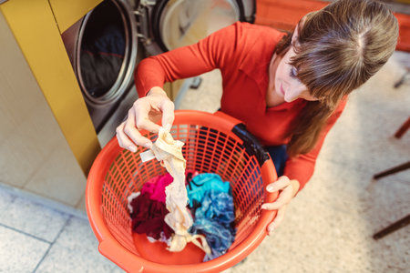 One woman loading her underwear into a washing machine in the laundromatの写真素材
