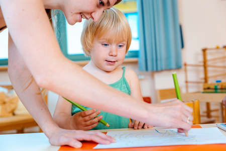 Children drawing with pencils in play school, the teacher helpsの写真素材