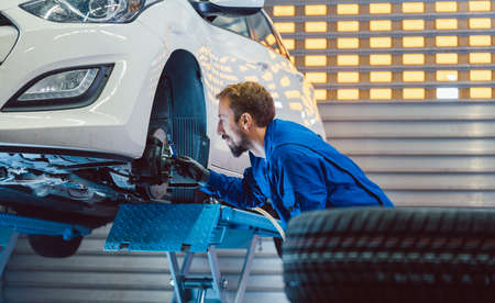 Car mechanic changing tire in his workshopの写真素材