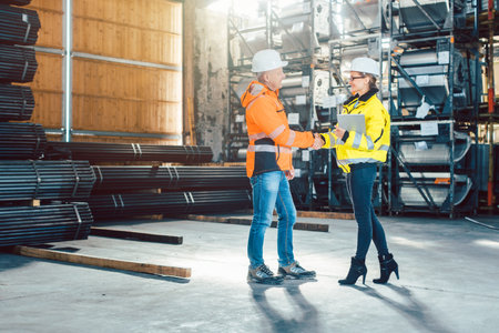 Handshake of worker and customer in warehouseの写真素材