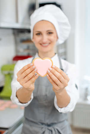 Pastry chef in love with her trade showing it with heart shaped sweetsの写真素材