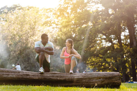 Black Caucasian couple stretching after exercise on tree trunk