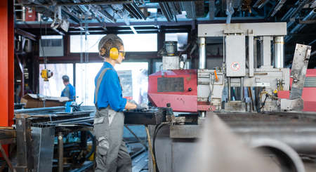 Woman worker operating a machine tool in metal workshop or factory