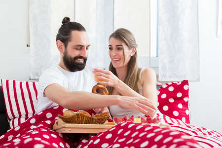 Young couple having breakfast in bedの写真素材