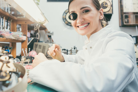 Watchmaker woman looking at camera in her workshop
