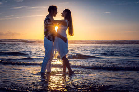 Romantic couple in love kissing on the beach during sunsetの写真素材