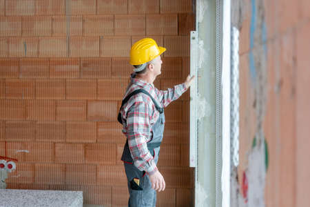 Senior male construction worker measuring the wallの写真素材