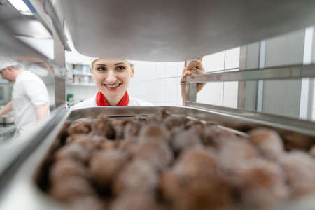 Women cook getting frozen meatball out of storage on a trayの写真素材