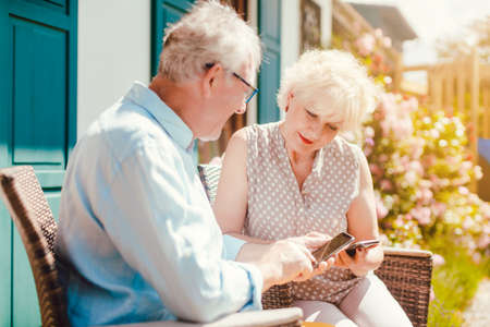 Senior couple looking at their phone in the gardenの写真素材