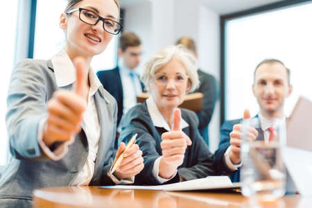 Business people showing thumbs up upon successful project