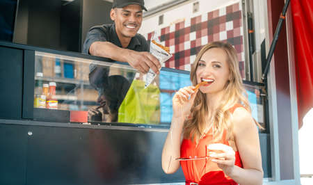 Beautiful woman ordering fries at a food truckの写真素材