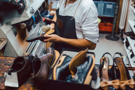 Shoemaker with shoes to repair on a rack in his workshopの写真素材