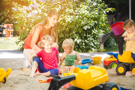 Children and play school teacher enjoying some time in sand boxの写真素材