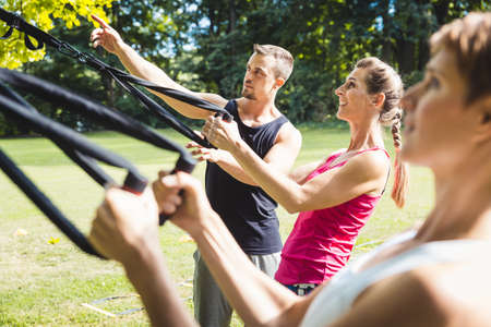 Personal trainer helping woman working with elastic resistant band