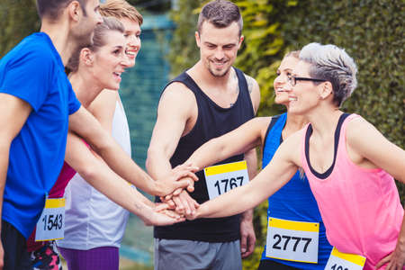 Group of marathon runners stacking handsの写真素材