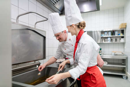 Chefs in large commercial kitchen cooking meals together
