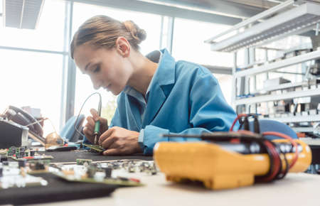 Worker in electronics manufacturing soldering a component