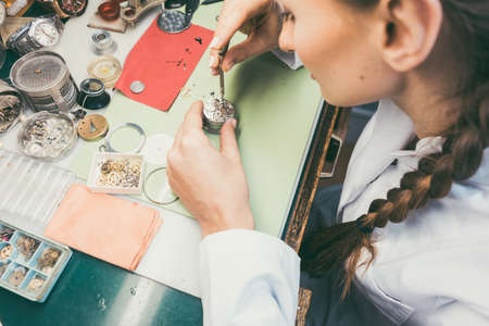 Woman watchmaker working diligently on repairing a watchの写真素材