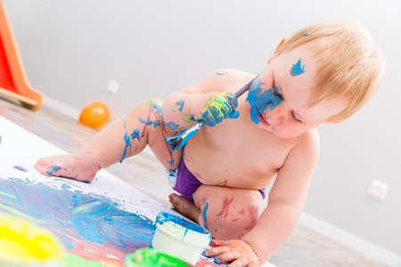 Cute baby painting with brush and paintの写真素材