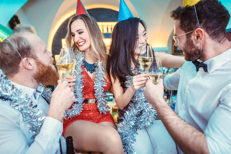 Happy couple and friends clinking champagne flute in barの写真素材