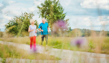 Fit and active senior couple running outdoors as exerciseの写真素材