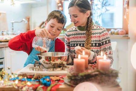 Boy mixing dough for Christmas cookies helping his motherの写真素材