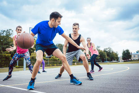 Group of friends are playing basketball outdoorsの写真素材