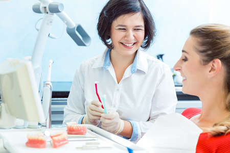 Dentist suggesting toothbrush to her patientの写真素材