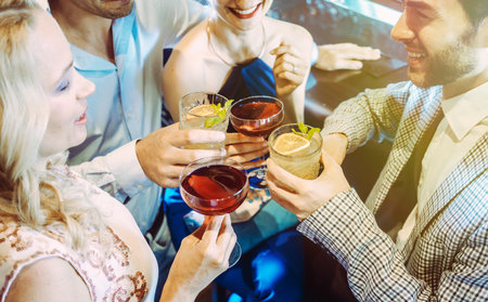 Women and men in a bar clinking glassesの写真素材