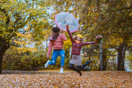 Man and woman jumping joyfully in the autumn parkの写真素材