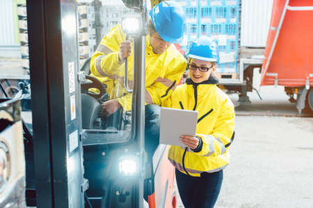 Forklift driver and forewoman discussing where to store deliveryの写真素材
