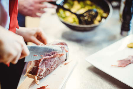 Detail shot of chef cook cutting Parma ham for use in a dishの写真素材