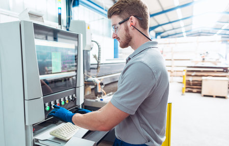 Worker operating a water jet cutting machine by pressing buttons
