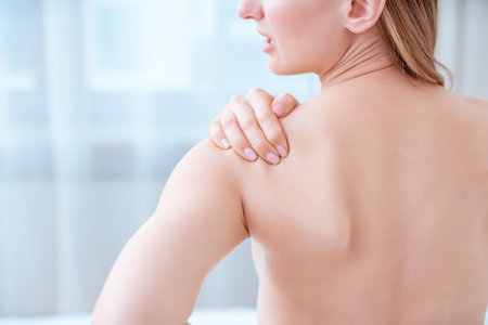 Woman holding hand at shoulder in pain