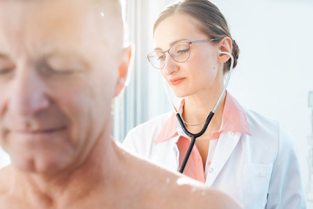 Doctor examining patient with stethoscopeの写真素材