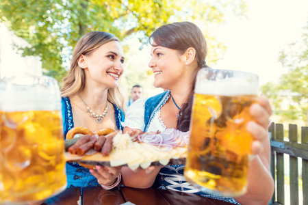 Two girls in Tracht with food in beer gardenの写真素材