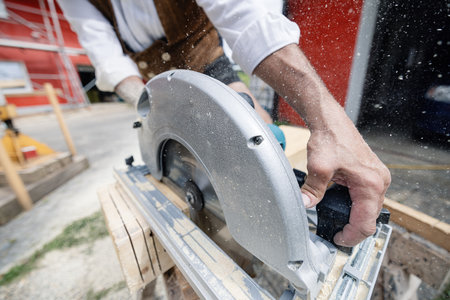 carpenter cutting wooden beam with electrical sawの写真素材