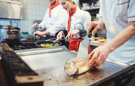 Team of chefs in a kitchen preparing fantastic food in pansの写真素材