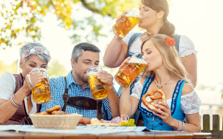 Waitress getting beer to patrons of Bavarian pubの写真素材
