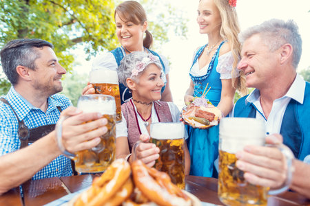 Group of friends in beer garden toasting to cameraの写真素材