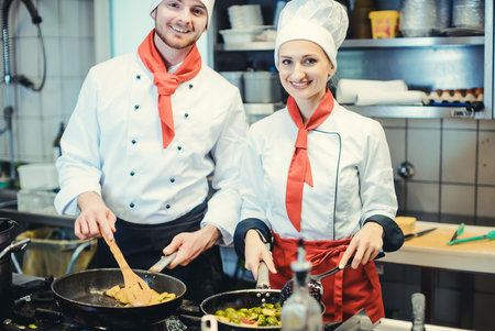 Team of chefs in a kitchen preparing fantastic food in pansの写真素材