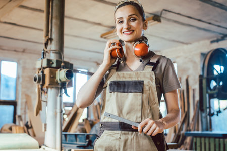 Beautiful woman carpenter in her woodwork workshopの写真素材