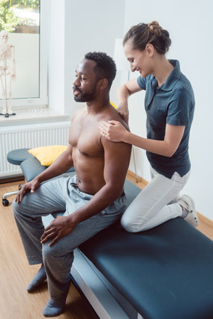 Physical therapist massaging a young man on shoulderの写真素材