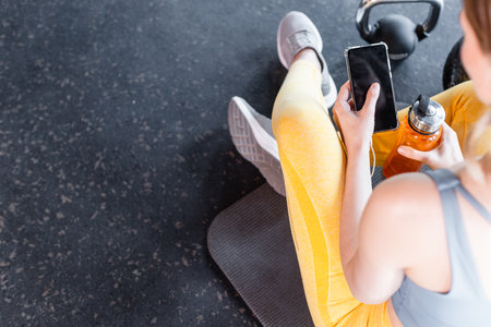 fit woman using app on phone in gymの写真素材