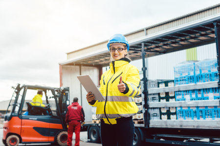 woman in front of forklift transporting goods from warehouseの写真素材