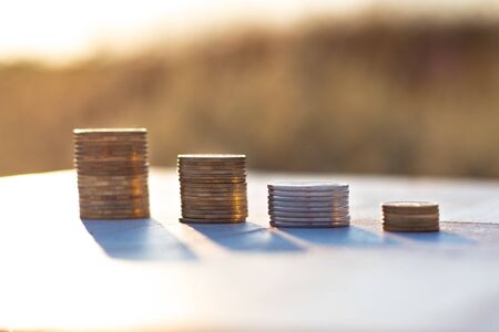 Stacks of coins laying down on the table on the beautiful sunset background, economy growth and strategy conceptの写真素材